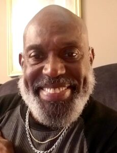 Black man with whitish beard and bald head smiling